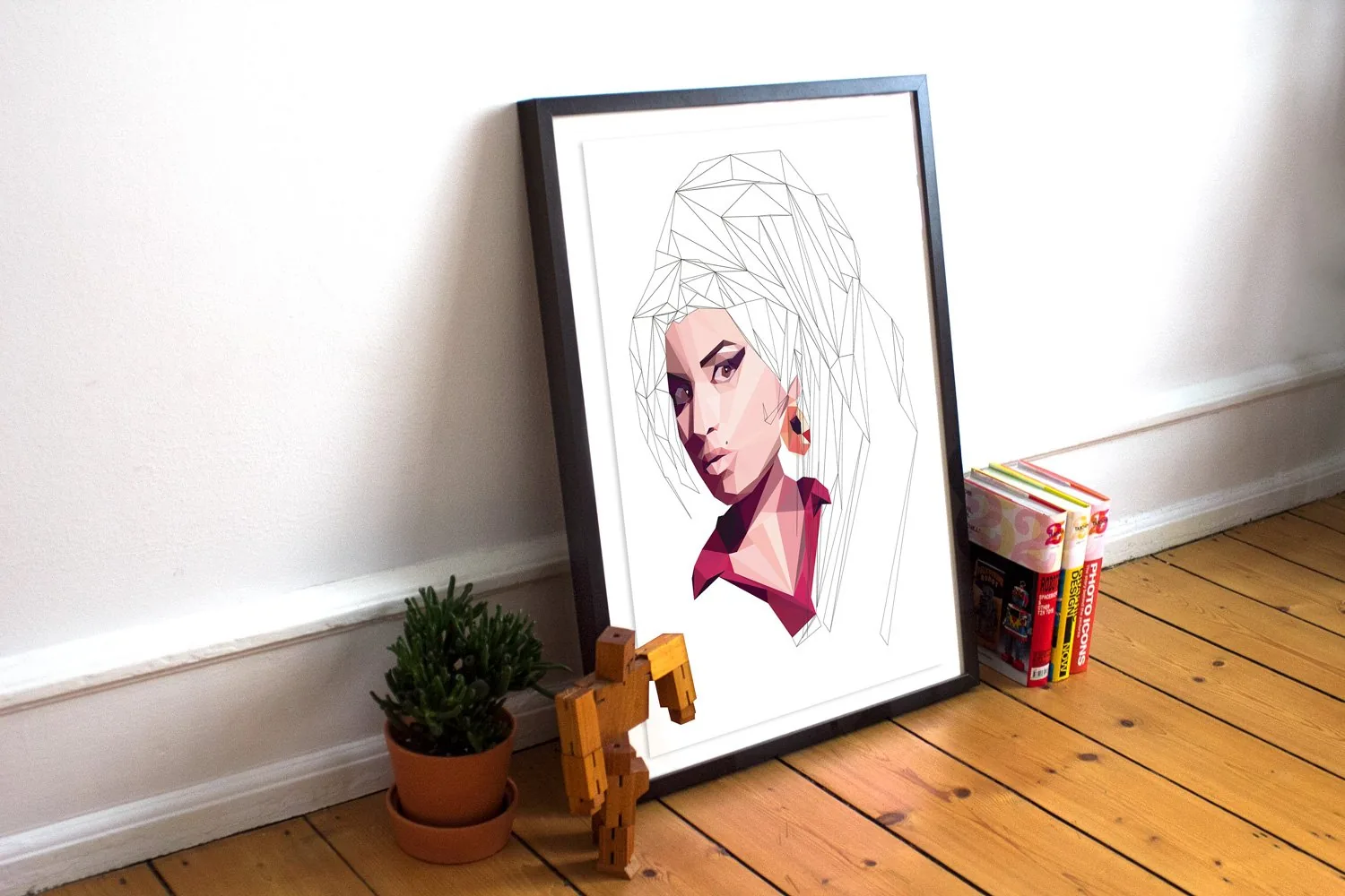 El retrato de Amy Winehouse impreso y enmarcado, apoyado en el suelo junto a una pared blanca.